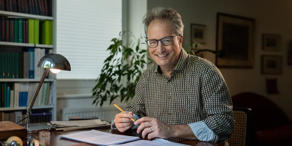 Wilm Hüffer sitzt lächelnd an seinem Schreibtisch